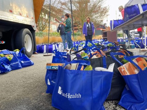 Several blue bags filled with Thanksgiving food wait to be delivered
