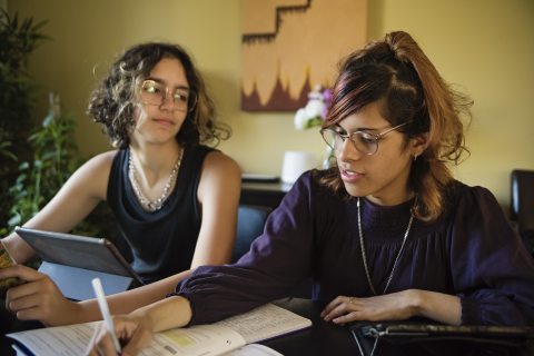 Two teenagers or young adults discussing a paper they're working on together
