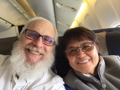 Bob and Cynthia smiling at the camera on a plane