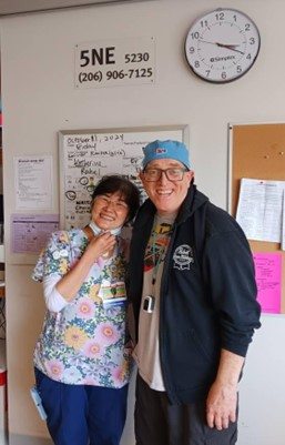 Bret standing and smiling with a caregiver 