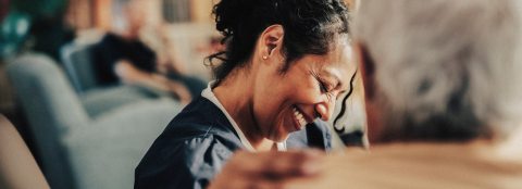 A nurse laughs with a patient in the foreground