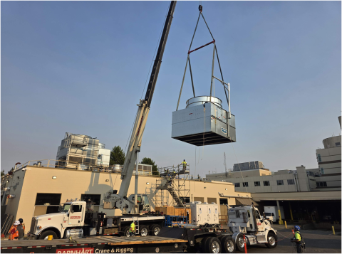A crane lifts a cooling tower onto the hospital roof