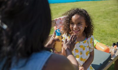 Woman applying sunscreen to a kid's face.