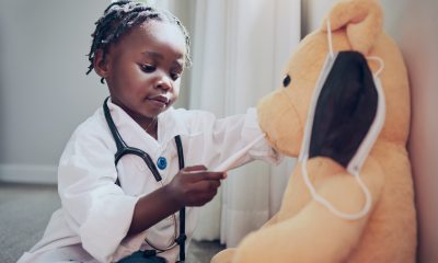 Young girl plays doctor with teddy bear