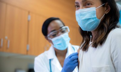 A young woman gets a flu shot in her right shoulder.