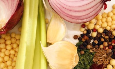 Closeup of garlic, onion slices, celery stalk, peppercorns and other spices