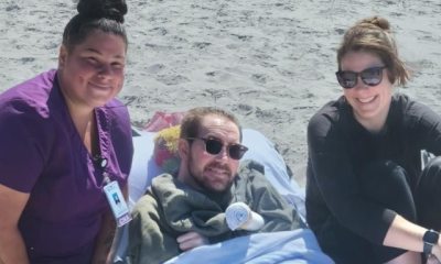 Aidan, Aidan's sister and caregiver Sandra Farris posing on the beach.