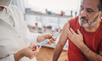 Pharmacy technician prepares to give vaccination to bearded man