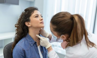 Woman doctor uses fingers to check the throat of a young woman