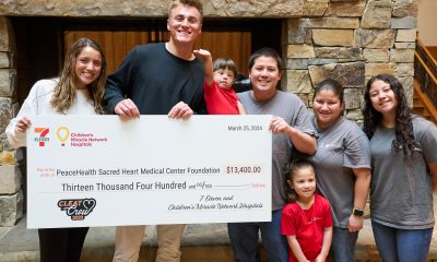 Quarterback Bo Nix, his wife, Izzy, and a local family who benefited from the Children's Miracle Network pose with a large check at PeaceHealth Sacred Heart Medical Center at RiverBend.