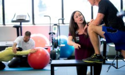 A physical therapist speaks with a patient during rehabilitation