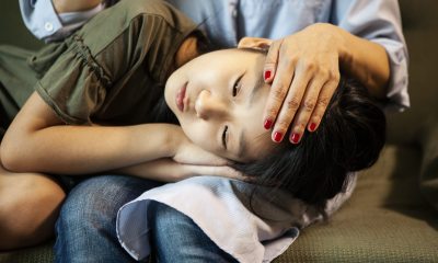 Close up of face of an Asian girl resting her head in the lap of a woman