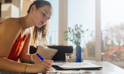 Woman writes notes on paper at coffee table