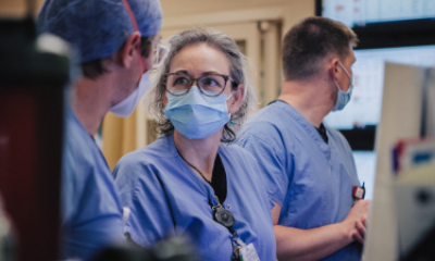 Three healthcare providers wearing blue scrubs and face masks.