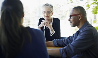 Three people facing each other around a table having a discussion