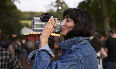Woman drinking water from a reusable bottle at an outdoor event