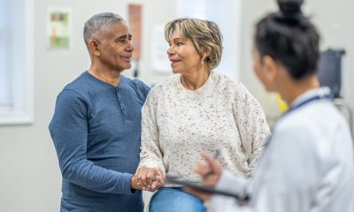 Man and woman smile at each other in exam room with doctor