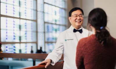 Dr Kim standing next to a window and smiling to a person whose back is to the camera