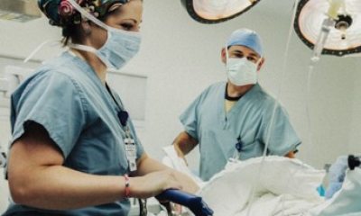 two caregivers standing next to a patient bed looking at the patient