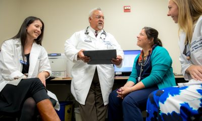 Dr. Ruiz stands and speaks with a group of other providers sitting in a room of computers