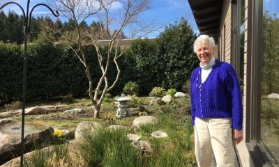 Carolyn Haugen stands near a garden on a sunny day
