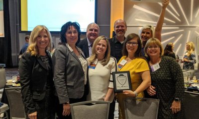 A group of eight PeaceHealth employees smiling and holding an award at a Healthiest Employer event