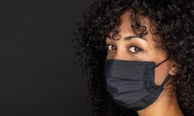 A masked woman looks into the camera