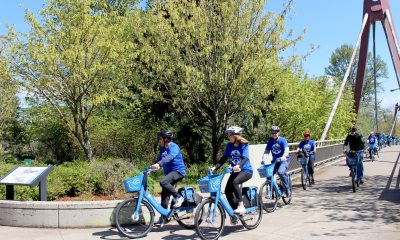 Caregivers cross a bridge on a sunny day on PeaceHealth Rides bicycles