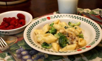 A plate of cheesy broccoli with raspberries on the side