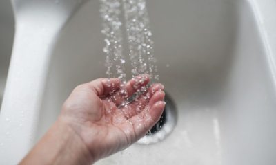 A person's palm held under running water over a sink
