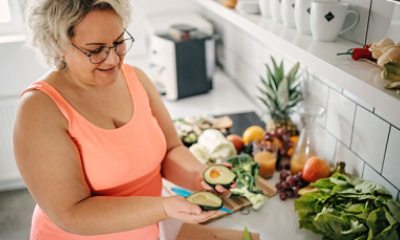 Woman opens a sliced avocado in her kitchen