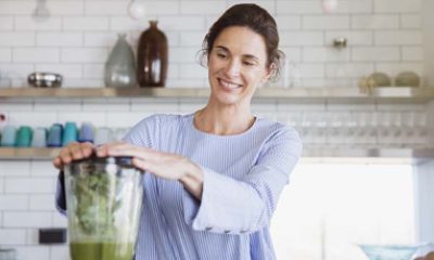A woman smiles while using a blender