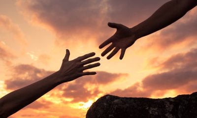 one person's hand reaching out to the hand of another person