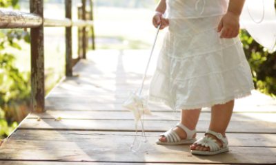 Young child in a white dress holding a toy magic wand with a star on the end