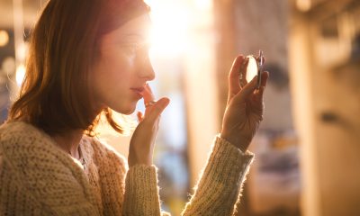 A woman looks into a pocket mirror to adjust make-up