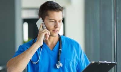 Healthcare provider in scrubs talks on the phone while looking at a patient chart