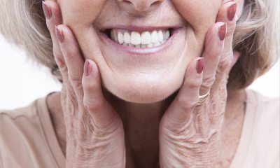 Older woman with a big smile resting her head on her hands