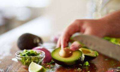 Close-up of a knife cutting an avocado and other vegetables