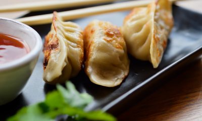Potstickers sitting on a plate next to sauce