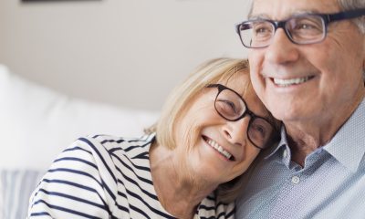 A woman rests her head on a man's shoulder, both are smiling.