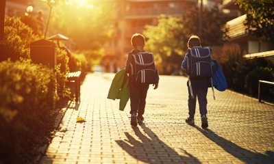 Two young boys with backpacks on with sunset in the background