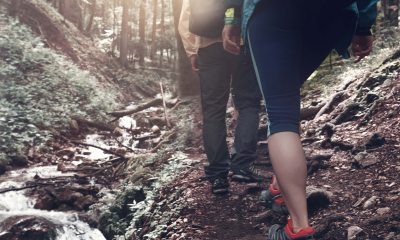 Two hikers traversing a creek in the woods