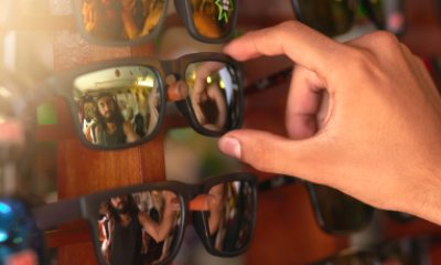 A person chooses sunglasses from a rack
