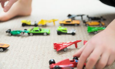 Close-up of young child's hands playing with toy cars and toy airplanes on the floor