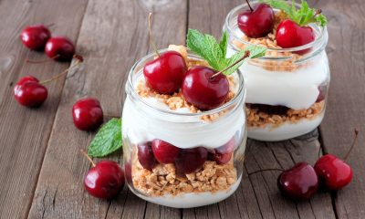 2 containers filled with cream, granola and cherries