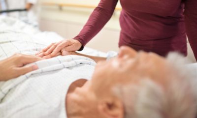 Woman comforting a male patient while he lays in a hospital bed
