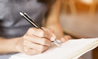 Close-up of hand and pen writing on paper