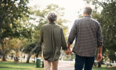 A hand-holding couple walks through a neighborhood lines with trees