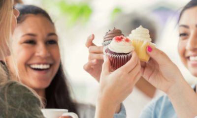 Smiling young women making a toast with frosted cupcakes instead of drinks