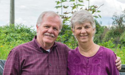 An older couple in matching colored outfits smiles for the camera